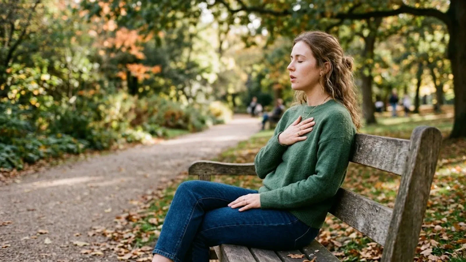 A woman on a park bench breathing slowly with a hand on her chest