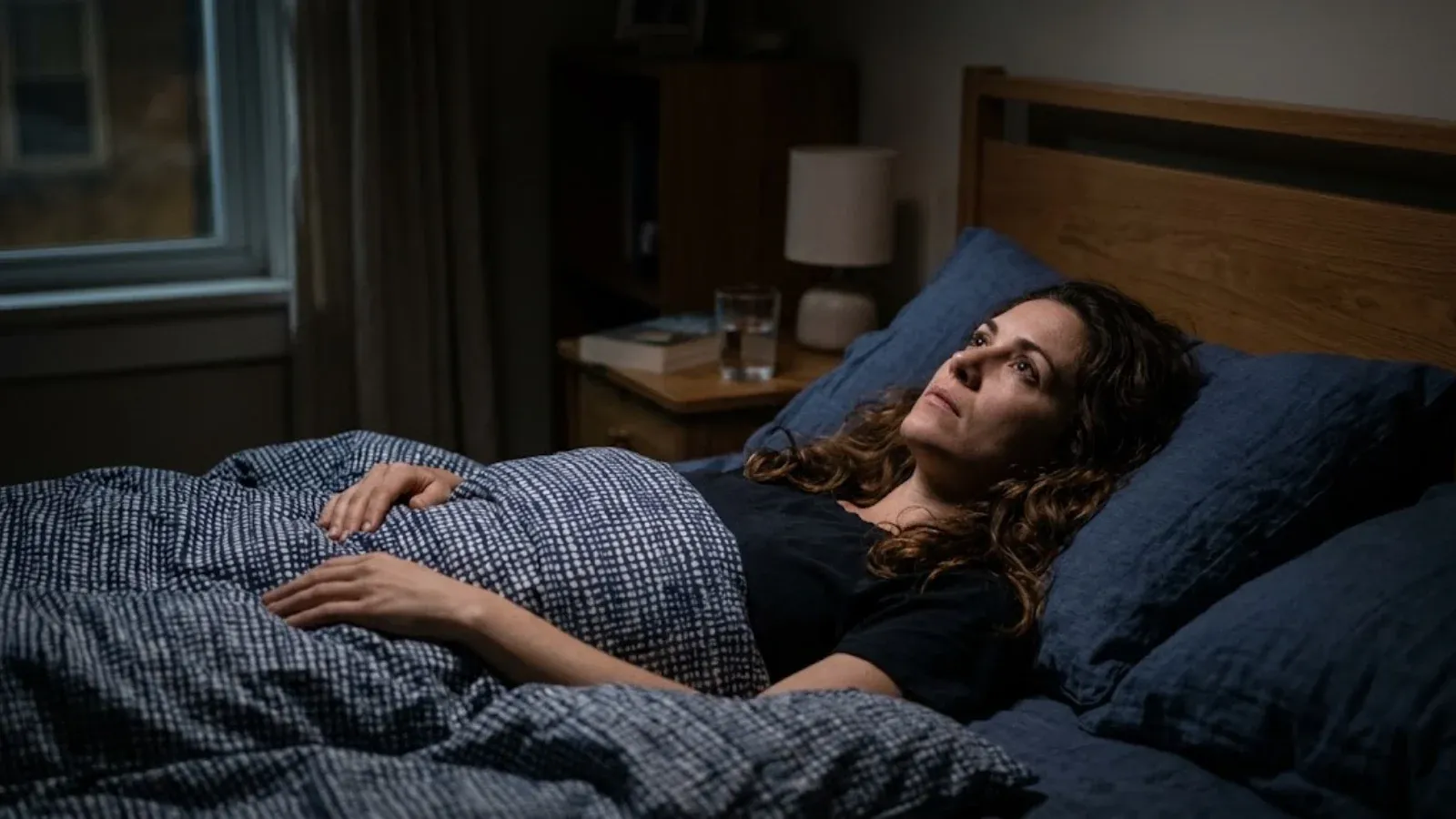 A woman awake in bed at night looking at the ceiling